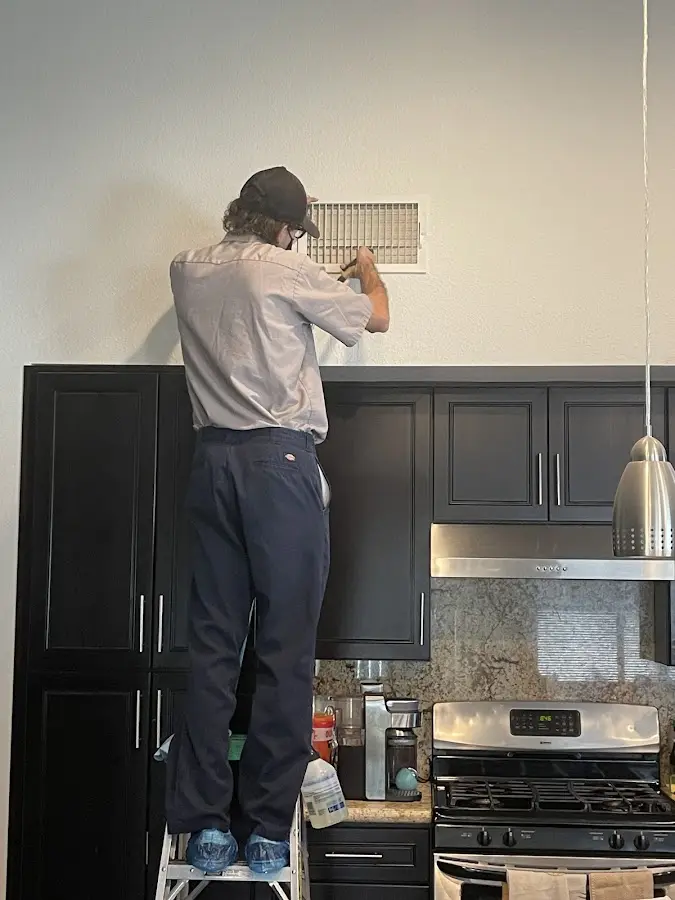 Technician inspecting an air vent during HVAC service in Graham